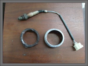Oxygen sensor shown on top. Old exhaust gasket on left. New gasket on right.